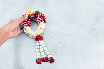 A woman' hand holding jasmine garland on white background