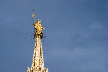 Fototapeta na wymiar Golden Madonnina: this statue is placed on the highest spire of the Milan cathedral (Duomo di Milano), Italy.