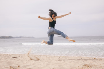 young cheerful woman jumping on the beach