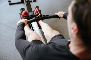 Back view of Athletic man using rowing machine