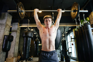 View from below of Athletic man holding barbell