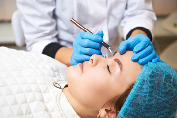 Permanent make-up wizard makes eyebrow correction procedure. Microblading