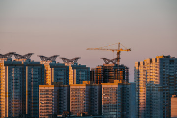 The construction of modern high-rise buildings at sunset light with crane, Voron