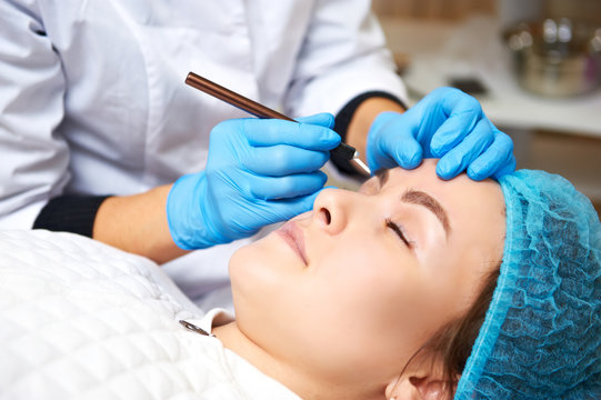 Permanent make-up wizard makes eyebrow correction procedure. Microblading