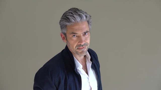 Handsome mature man standing on grey background, isolated