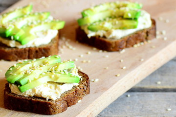 Vegan avocado and hummus sandwiches on a wooden board. Quick and healthy open sandwiches. Healthy eating. Meatless meal. Closeup