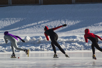 Speed skating competition on ice rink at winter sunny day - children's sport concept