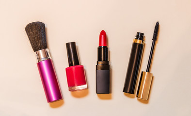 Brush, nail polish, lipstick and  mascara on beige background