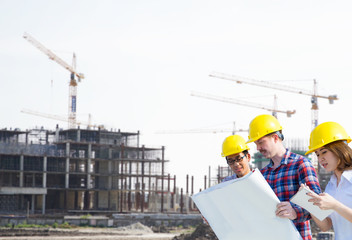 Engineer group and worker meeting, discussion with construction blueprint on site work background