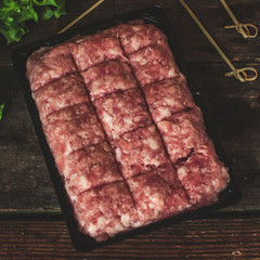 Minced meat in a package on the table and lettuce leaves