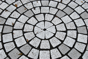 Stone floor with grey color and radiation patterns. Circular pavement.