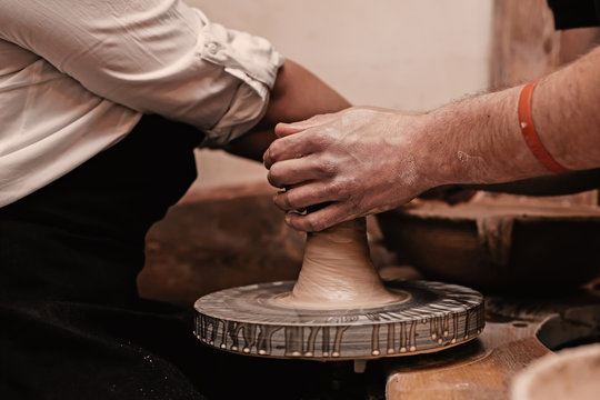 Closeup of hands working on pottery wheel