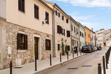 Deserted narrow street of the old town Vrsar in Croatia. Rows of low-rise houses with nice naive flowers on window sills.