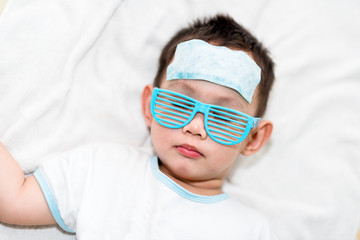 The kid attach cooling gel pad on his forehead