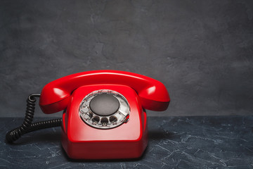 landline red phone on a gray wall background