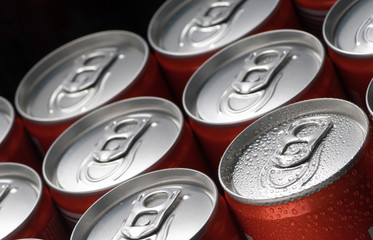 a group of red tin cans with water droplets closeup on a black background
