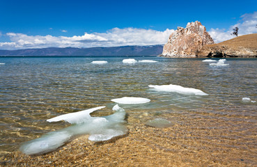 Lake Baikal on a spring morning. Olkhon Island. Ice floes on clear water near the Shamanka Rock
