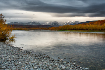 The gloomy sky over the mountains and river. Autumn in the polar Urals.