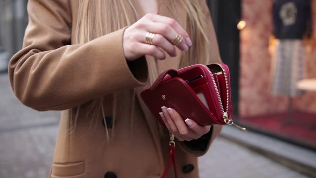 Elegant woman's hand opening red purse outdoors