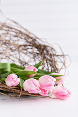Pink tulips in basket on white table