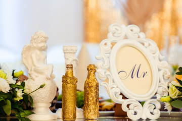 Curly photo-frame with lettering 'Mr' inside stands on dinner table