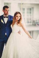 Luxury wedding couple stands before panoramic window