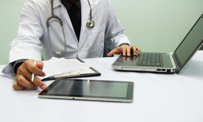 medicine doctor working with computer notebook and digital tablet  at desk in the hospital