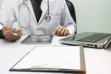 medicine doctor working with computer notebook and digital tablet  at desk in the hospital