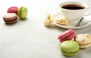 Cup of black tea with varicolored macaroons  on a white background in light key. Copy space.