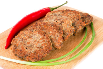 liver pancakes or cutlets with chilli and spring onions on a cutting board isolated white background