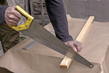 Fototapeta na wymiar Carpenter using a hacksaw to cut piece of wood