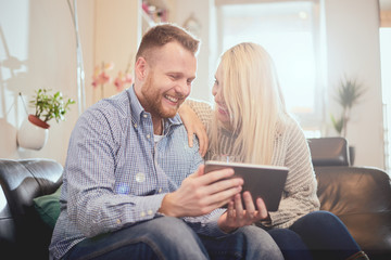 Couple looking at tablet computer while siting on sofa