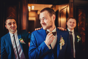 Stylish groom and groomsmen pose in the room