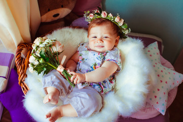 Pretty little girl lies with roses on fluffy pillow in the basket