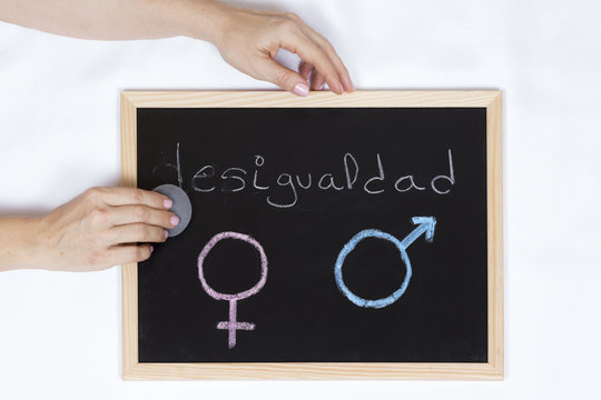 Hands of woman holding and erasing the word inequality on a blackboard with the symbol of gender equality
