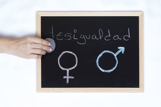 Woman hands erasing the word inequality on a blackboard with the symbol of gender equality
