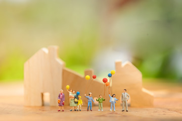 Miniature people, family and children with colorful ballons  standing in front of house. International Day of Families