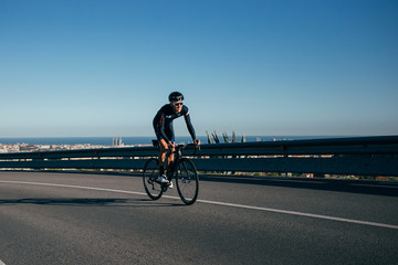 A fit strong cyclist climbs a road overlooking Barcelona, spain © onewithahalf
