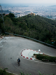 Naklejka premium A professional cyclist descending a technical corner near tibidabo park, high above barcelona, spain