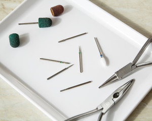 Medical equipment. Burs for podiatry, red and green caps, cutters on the white tray