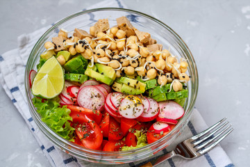 Colorful vegetable salad with tofu, chickpeas, avocado in a glass bowl. Love for a healthy vegan food concept