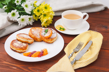 cheese pancake with citrus fruits and jam on a wooden table with tea. Breakfast concept
