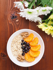 Oatmeal with fruit and berries on a wooden background.