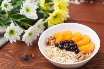 Oatmeal with fruit and berries on a wooden background.
