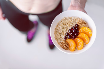 Oatmeal with fruit berries and cereals in the hands of a sportswoman