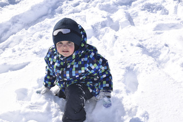 Fototapeta na wymiar Cute little boy wearing warm clothes playing on beautiful winter snowy day