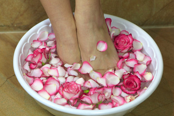 Obraz na płótnie Canvas Woman bathes her feet in a bowl with rose petals