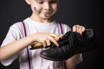 Boy cleans dirty shoes