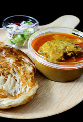 red curry chicken serve with roti and sour sauce on black background