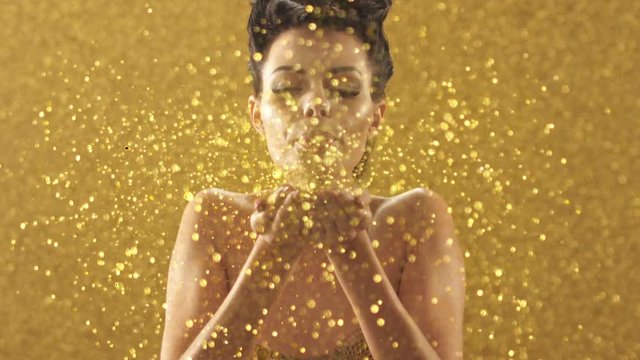 Beautiful brunette woman blowing gold glitter, Red Epic 4k slow motion